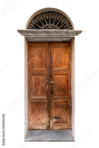 Old weathered double wooden door with a warm brown texture, featuring a classic arched stone lintel and a decorative black wrought iron security grille in the lunette above, isolated