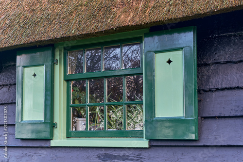 Foto Traditional Dutch architecture, green window shutters on a historic thatched roo