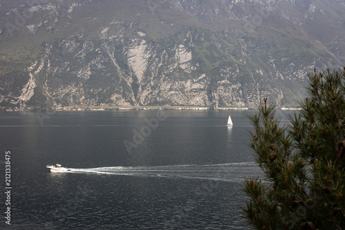 Motorboat and Sailboat on Lake Garda Beneath Dramatic Mountain Cliffs, Italy