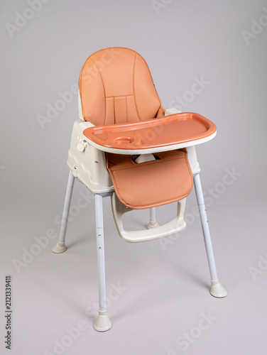 Dark orange baby high chair with tray on grey background