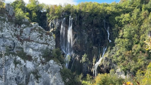 Plitvica Selo, Croatia - October 06, 2025: Plitvice Lakes National Park, Croatia. Waterfall cascading into tranquil lake surrounded by lush greenery and rocky formations in serene natural setting