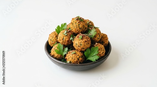Crispy falafel balls with parsley garnish presented in a dark bowl on a white surface fried chickpea fritters middle eastern