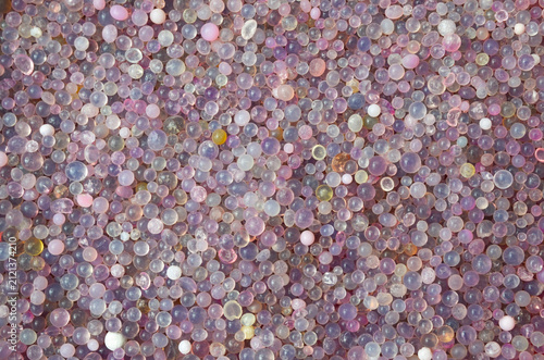 Close up full frame background texture of colorful purple and pink silica gel desiccant beads.