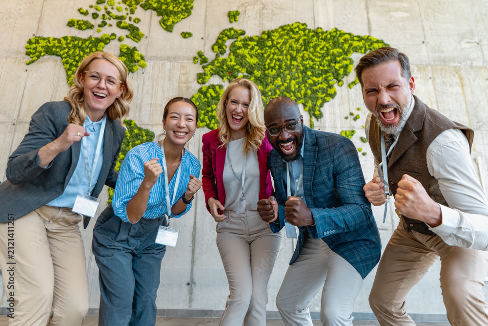 Fototapeta premium Team celebrates success at a corporate event in a modern office with a green world map wall
