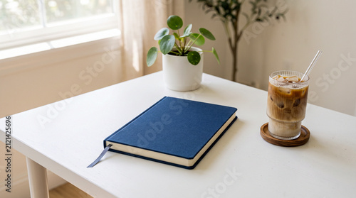 Minimal Workspace with Closed Blue Notebook Planner and Iced Coffee on White Desk Mockup