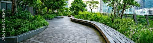 Urban rooftop garden walkway city park green modern outdoor landscape urban rooftop garden walkway city park green modern outdoor landscape with curved wooden path lush plant and tree foliage