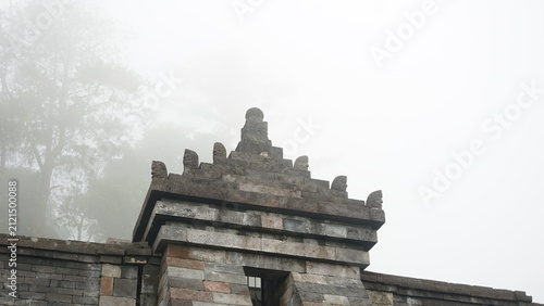 Fotografía Ancient Stone Gate of Candi Cetho Shrouded in Morning Mist, Central Java, Indone