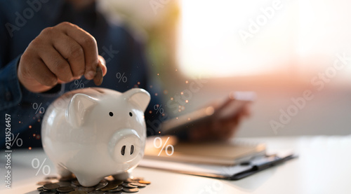 Hand putting coins into a piggy bank saving bank for account save money percentage. Planning step up, saving money for future plan, retirement fund. Business investment-finance accounting concept.