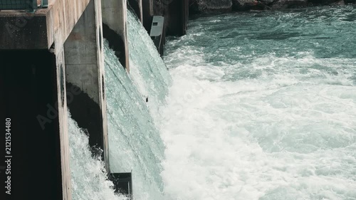 Powerful rushing water released through the concrete spillway of a hydroelectric dam, representing renewable energy production, water management and sustainable infrastructure