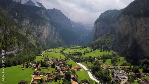 Iconic Lauterbrunnen village in Switzerland. cinematic aerial drone 4k footage view green valley village vertical rock cliffs waterfall sunny day. Bernese Oberland travel destination