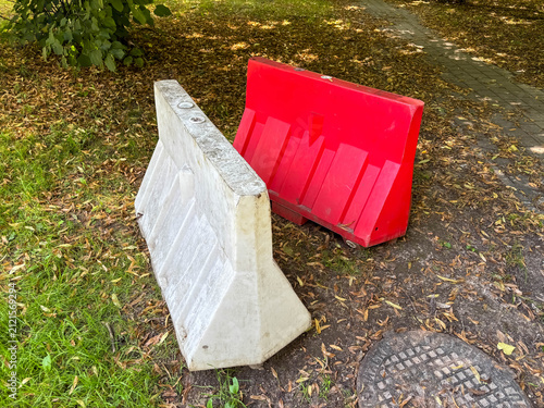 Obraz na plátně White and red temporary traffic barriers positioned beside a grassy walkway, public safety and municipal construction control