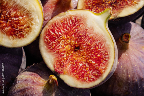 Whole and sliced ripe figs with vibrant pink flesh and sparkling water droplets. Fresh Ficus carica fruit showcasing natural sweetness, healthy nutrition, organic produce and premium food styling.