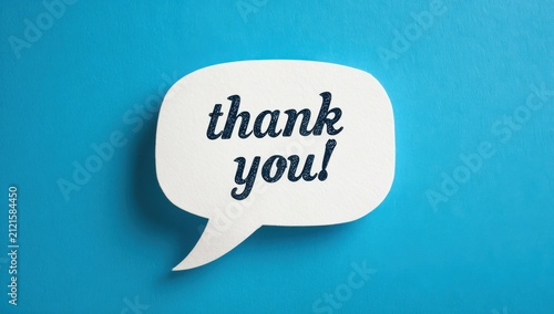 Small thank you paper speech bubble cutout on a textured blue surface with gratitude appreciation handwriting creative business customer feedback positive kindness expression
