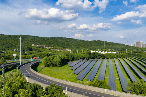 Solar panels beside curved road under blue sky