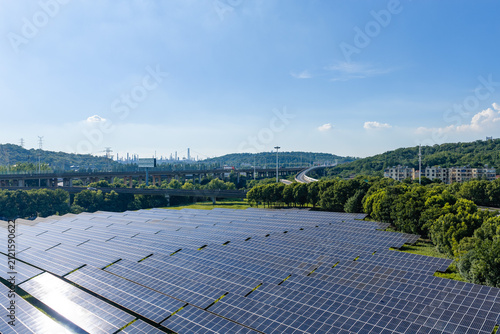 Wide solar panel farm beside wooded hills