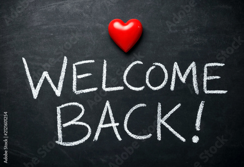 Chalkboard with welcome back message and red heart symbol written in white chalk