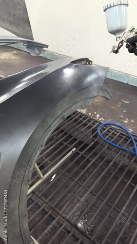 Automotive body part receiving a fresh coat of metallic paint in a spray booth