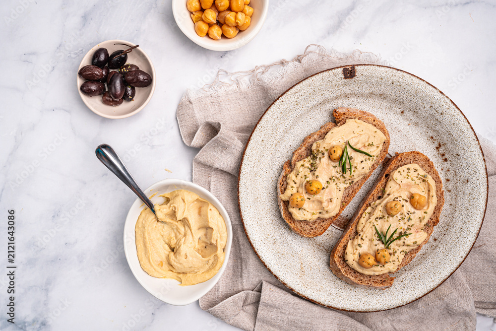 Obraz premium Delicious sandwiches with hummus and ingredients on white table, top view, flat lay. High quality photo