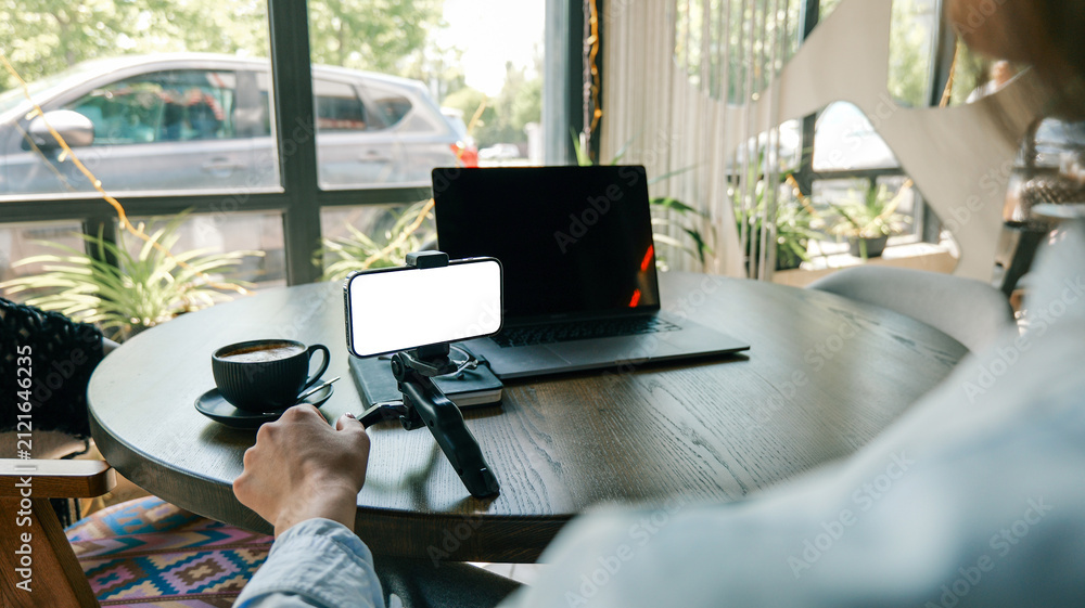 Obraz premium Person working remotely with laptop and phone on a cafe table with coffee