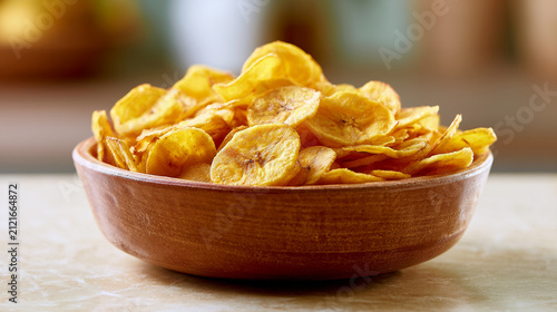 Bowl of crispy fried banana chips on a wooden table