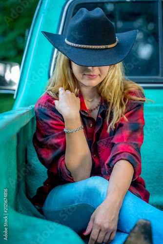 Golden Hour Country Lifestyle Portrait of a Beautiful Young Cowgirl Leaning Against a Modern Pickup Truck in Warm Evening Sunlight