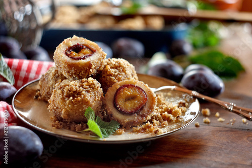 Fotografie Homemade sweet plum dumplings with breadcrumbs, walnut and cinnamon on a wooden