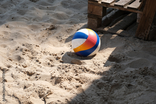 Beach volleyball resting on sandy court in sunlight