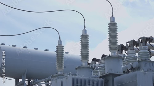 Slow motion panning of high voltage transformer insulators and busbars at outdoor electrical substation, steady left to right tracking shot.