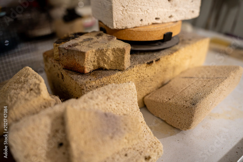Foto Broken pieces of porous refractory firebrick and a round ceramic kiln shelf resting on a workbench in a pottery workshop, used for high temperature insulation