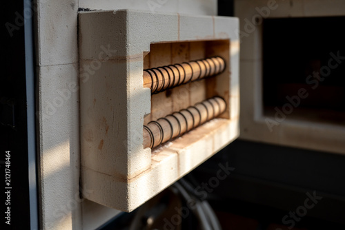 Konstfotografi Heating coils and refractory firebrick inside open door of electric muffle furnace in ceramic art workshop, representing thermal processing equipment