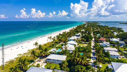 Aerial View of a Tropical Beachfront Community with Turquoise Ocean and White Sand.