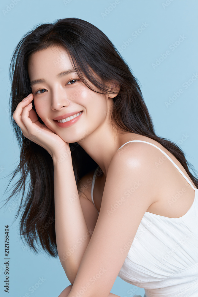 Fototapeta premium young east asian woman with glowing skin in elegant white dress, serene portrait of young asian woman with radiant skin and soft smile, natural beauty portrait of young east asian woman on pastel blue