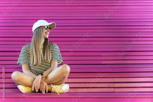 Woman in summer outfit sitting on bright pink city steps