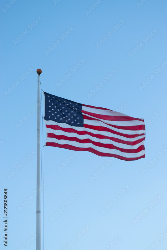 Obraz premium US American flag waving in the wind with beautiful blue sky in background. American flag on blue sky USA. Flag waving. Independence day. 4th of july. Vote