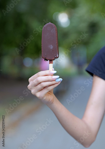 Woman holding chocolate ice cream bar outdoors on summer day