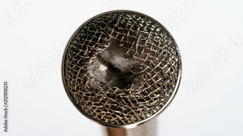 Close-up of a damaged and crushed microphone grille with a hole in the metal mesh