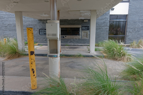 Quadro su tela An abandoned bank drive-through with a closed ATM and teller window set in a wea