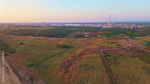 Oil refinery and green landscape in Sines, Portugal at sunset. Aerial view, distant shot. Moving forward