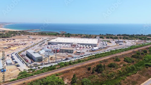 Data center building and expansion site under construction near the coastline in Portugal. Green landscape and Atlantic ocean. Aerial view. Orbiting