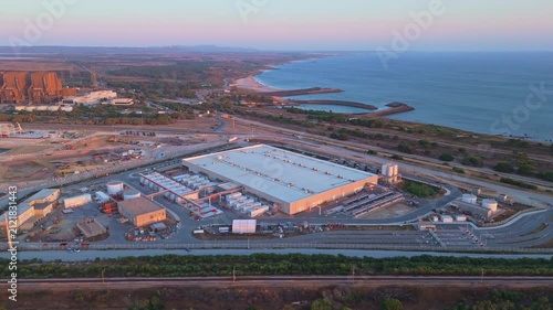 Data center building and expansion site under construction near the coastline in Portugal at sunset. Green landscape and Atlantic ocean. Aerial view. Moving sideways