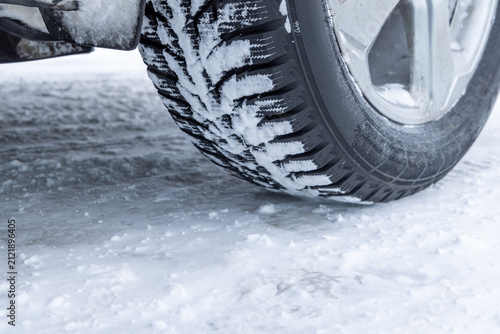 Canvastavla Close-up of a winter vehicle tire resting on a snow-covered icy road, showcasing tread and cold weather conditions