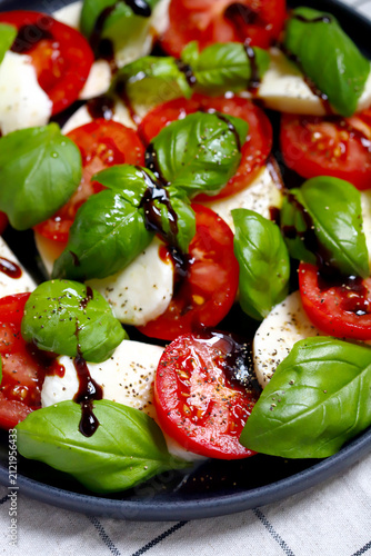 Caprese salad on a black plate with balsamic vinegar