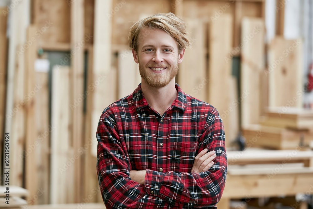 Obraz premium Smiling Craftsman in Plaid Shirt with Arms Crossed in Woodworking Workshop