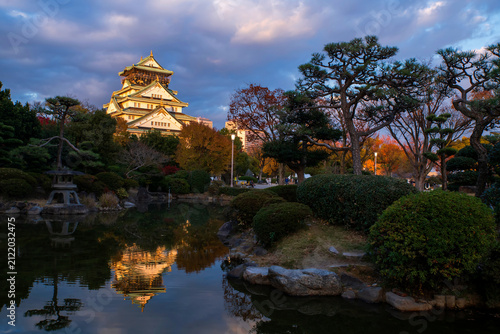 Iconic Osaka Castle by garden with skyline reflection on pond at dusk