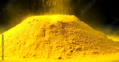 Vibrant Yellow Turmeric Spice Powder Pouring Creating a Bright Mound Against Dark Background.