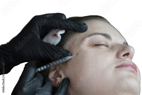 woman lies in an armchair, receiving a cosmetic injection, a close-up of a rejuvenating injection in the forehead