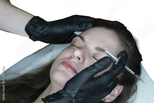 woman lies in an armchair, receiving a cosmetic injection, a close-up of a rejuvenating injection in the forehead