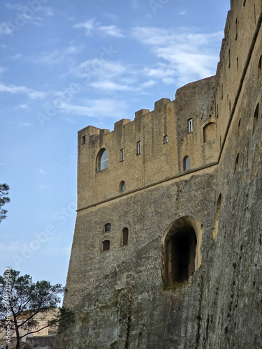 Obraz na płótnie Low angle view of the massive stone walls and crenellated ramparts of Castel Sant'Elmo against a blue sky in Naples, Italy