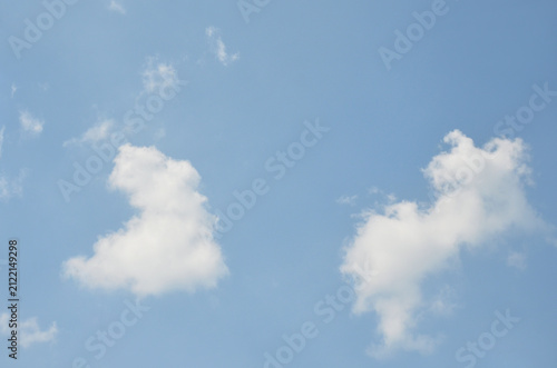 Fotografie Two fluffy white clouds drifting against a clear blue sky