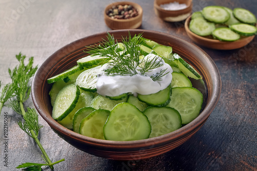 Eine Schüssel mit Gurken in Schheiben geschnitten und darüber lecker Dressing für einen Salat